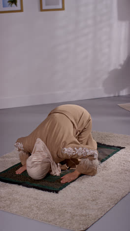 Vertikales-Video-Einer-Muslimischen-Frau-Mit-Hijab,-Die-Zu-Hause-Kniend-Auf-Einer-Gebetsmatte-Betet-5
